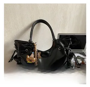 Détail d'un sac cabas noir brillant avec fermeture à cordon et pendentif ours mignon