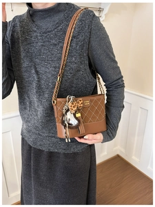 Detailed shot of quilted brown hobo bag with heart charm and leopard bow on strap