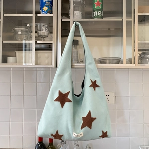 Detail of light blue plush tote bag with brown star embroidery and woven label