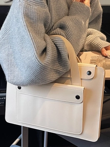 Minimalist cream white laptop tote bag with front pocket held by model in winter outfit
