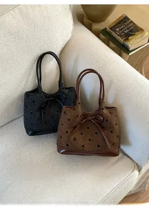 Détails des sacs cabas en tweed à pois avec nœuds décoratifs posés sur un canapé doux