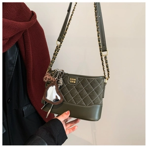 Close-up of olive green quilted handbag featuring a leopard print heart mirror charm
