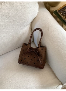 Gros plan du sac en toile rétro marron avec pois noirs et détail de nœud en cuir sur canapé
