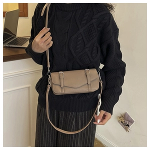 Detail shot of light brown litchi pattern leather crossbody bag with metal buckles