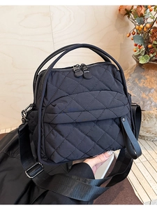 Dettaglio della texture in nylon trapuntato nero con doppie cerniere e tasca capiente