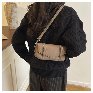 Close-up of khaki litchi grain leather crossbody bag with silver buckles and strap
