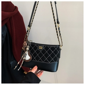 Detail of diamond lattice stitching on black crossbody bag with chain strap and heart charm