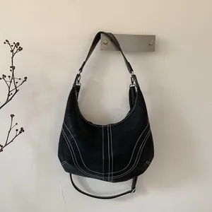 Detail of vintage black half-moon hobo bag with contrast white stitching and adjustable strap