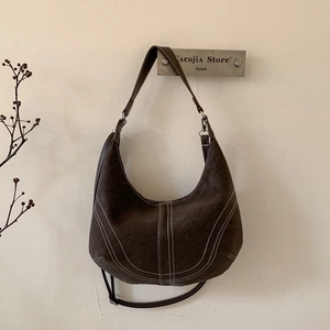 Detail of vintage brown hobo bag with contrast stitching and adjustable strap