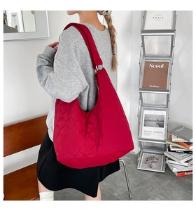 Détail du sac fourre-tout matelassé rouge montrant les coutures en losange et le volume