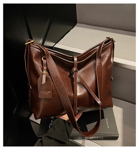 Close-up of dark brown oil wax leather tote bag texture and branded square tag detail