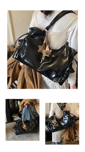 Détail du sac bandoulière noir brillant avec cordons latéraux et breloque en peluche