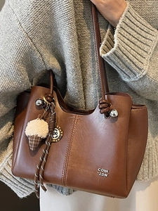Brown leather shoulder bag with vertical stitching and cute ice cream charm on model