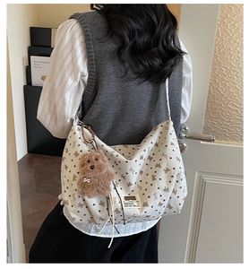 Detail der weißen Cord-Hobo-Tasche mit Herzmustern und einem Plüschbär-Anhänger-Charm
