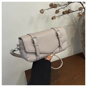 Close-up of pebble leather texture on stylish crossbody bag with metallic strap buckles