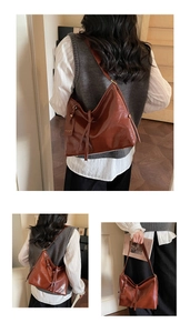 Detailed close-up of brown faux leather tote bag with gold logo tag and side strap