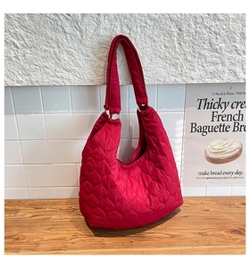 Vue détaillée du sac cabas matelassé en nylon rouge avec forme en croissant et bandoulière
