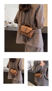 Detail view of a vintage brown leather crossbody bag with a metallic flap clasp and handle