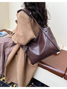 Detail of soft dark brown leather tote bag featuring stylish side tassels on model