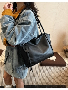 Close-up of black leather tote bag with elegant tassel detail and soft matte texture
