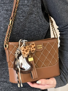 Brown quilted crossbody bag with metal chain strap and leopard bow charm for women