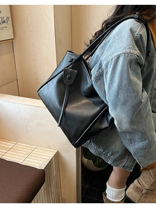 Detail view of black matte leather tote bag with long decorative straps and snap closure