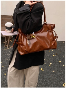 Détail du sac cabas en cuir marron foncé avec cordon, poche latérale et breloque ours