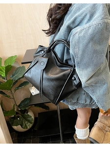 Detail of black leather tote bag featuring a unique folded structure and stylish leather tassel