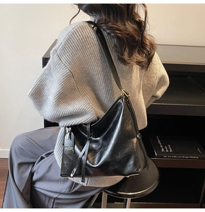 Detail view of large black glossy tote bag with leather drawstring and metal buckle