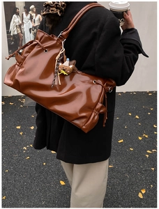 Détail du sac cabas en cuir marron foncé brillant avec cordon de serrage et pendentif