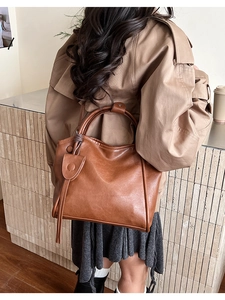 Detailed view of the large brown leather tote bag with stylish fringe and solid handles