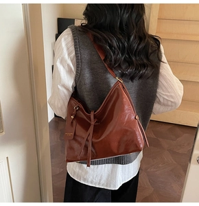 Close-up of brown leather tote bag with drawstring knot and branded tag detail