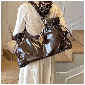 Détail d'un sac à bandoulière en cuir marron foncé brillant avec cordon et pendentif d'ours