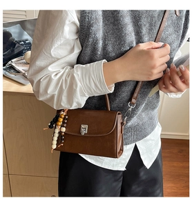Detailed view of retro brown crossbody bag with metallic clasp and beaded charm accessory