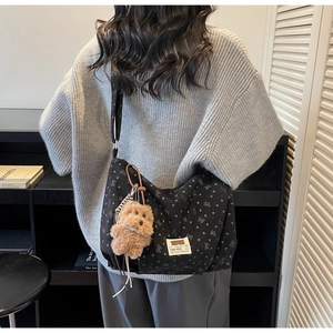 Detail einer großen schwarzen Totebag mit Herzmuster und braunem Plüschbär-Anhänger