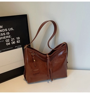 Detailed close-up of dark brown hobo bag with adjustable strap and vintage logo tag