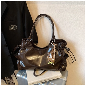 Détail d'un grand sac cabas marron foncé brillant avec cordon de serrage et ourson
