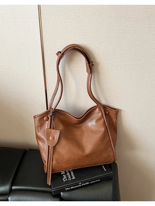 Detailed texture of brown soft leather tote bag on black bench with minimal wall background