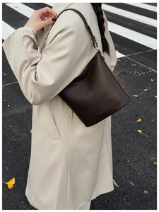 Dunkelbraune Lederbeuteltasche getragen zu einem beigen Trenchcoat im Herbstlook
