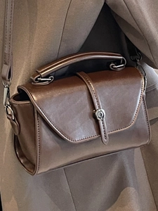 Retro dark brown leather handbag with top handle and crossbody strap worn with a blazer