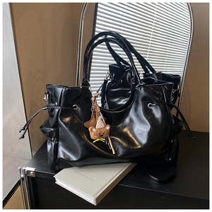 Détail d'un sac cabas noir brillant avec cordons latéraux et breloque étoile sur miroir
