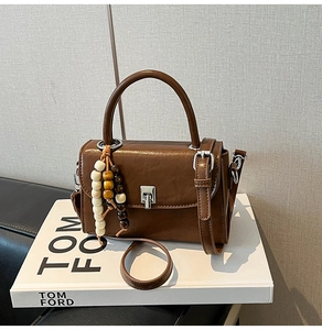 Detail of brown vintage leather handbag with metal buckle and wooden bead tassel accessory