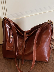 Minimalist caramel brown leather tote bag with a high-shine finish and golden hardware