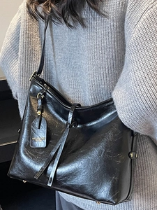 Minimalist black leather tote bag with fringe detail and metal charm for women's daily commute