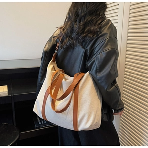 Detailansicht der Kontrastnähte an beiger Canvas-Tasche mit braunen Ledergriffen