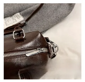 Macro shot of polished silver hardware and dark brown faux leather on a Boston bag
