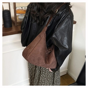 Brown large capacity tote bag with suede texture shown on shoulder in daily scene