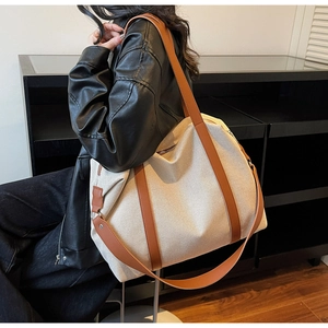 Nahaufnahme der cremefarbenen Canvas-Tasche mit braunen Lederriemen am Model