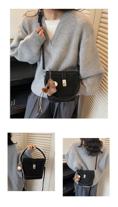 Detail of minimalist black bucket bag with silver twist lock and horse charm pendant