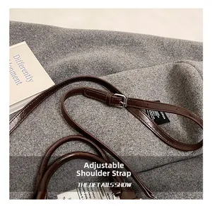 Detail view of adjustable dark brown leather shoulder strap with silver buckle and fine stitching